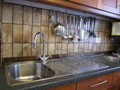 Portion of the kitchen with shining stainless steel frankie sink and mixer tap
