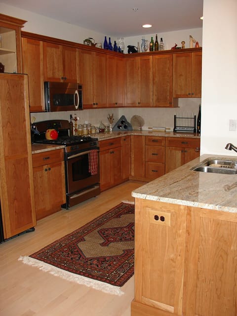 Kitchen with cherry cabinets and fully equipped pantry across from SS gas range.
