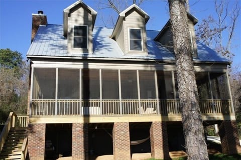 View of house from the lake.  Screened porch, metal roof, and hammock below.