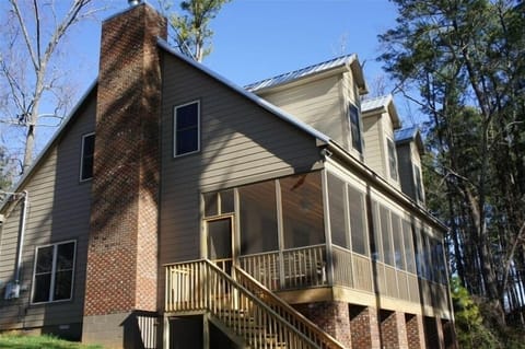 View from back yard shows chimney, screened porch, and stairs.