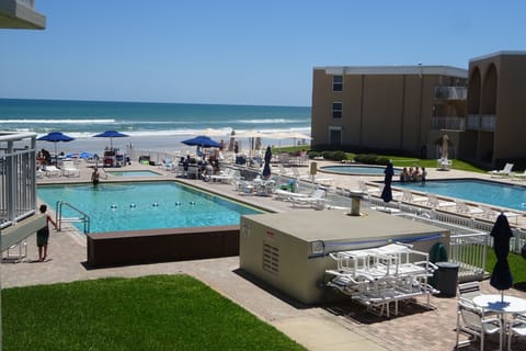 View from apartment balcony of barbecue area, pool & beach.