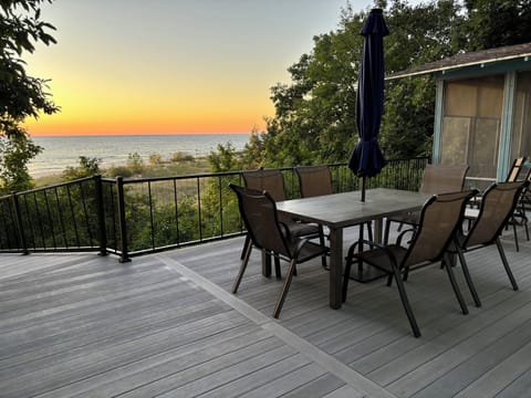 Deck and screen porch with view of Lake Michigan at sunset.