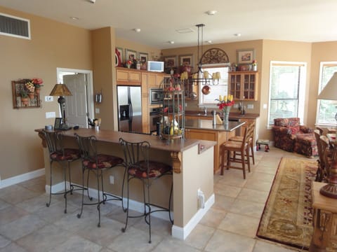 Open kitchen with bar height counter with 3 wrought iron bar stools