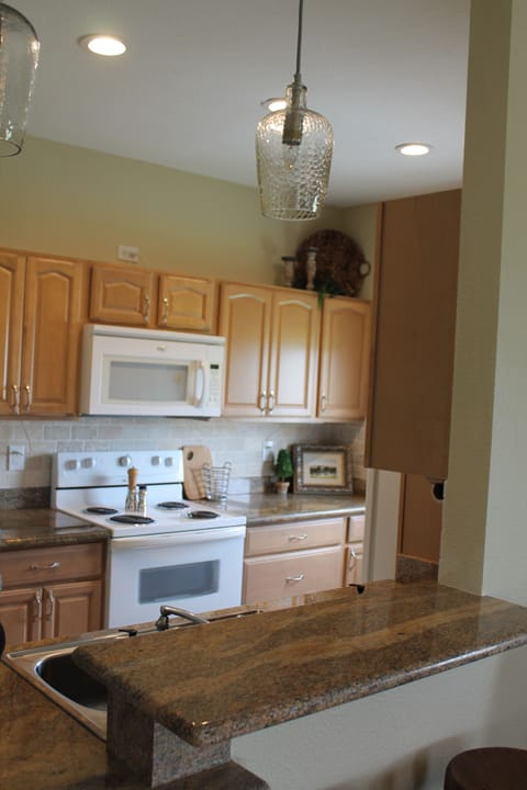 Kitchen open to living area with 4 stools at bar