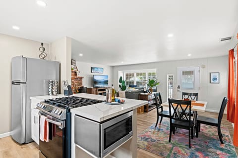 Enjoy cooking in this bright, modern kitchen with sleek white cabinetry, quartz countertops, and bar seating for casual meals or morning coffee. Fully stocked for all your culinary needs.