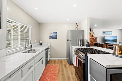 Enjoy cooking in this bright, modern kitchen with sleek white cabinetry, quartz countertops, and bar seating for casual meals or morning coffee. Fully stocked for all your culinary needs.