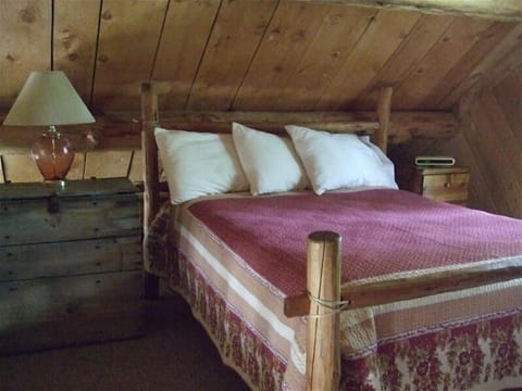 Upstairs loft with hand-hewn log bed accessed by spiral staircase-open to below.