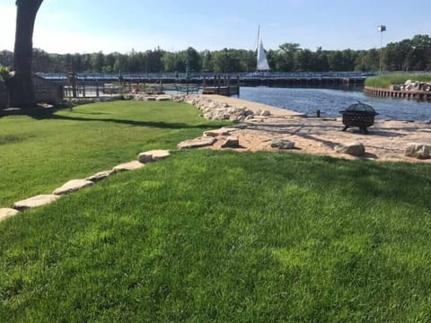 Grassy backyard with docks and fire pit. 