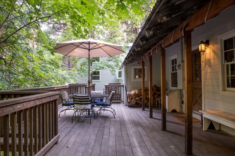 Deck above creek on front of house with outdoor dining table