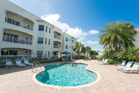 - Sparkling outdoor pool with palm trees and lounge seating nearby  
- Perfect for swimming, sunbathing, or unwinding on warm afternoons  
- Enjoy tropical vibes just steps away from your beach condo stay 