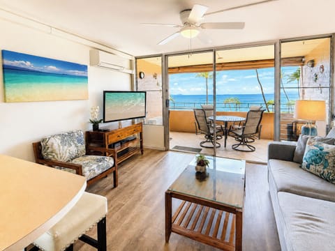 Golden hour light floods this oceanfront living room as palm trees sway just beyond the lanai
