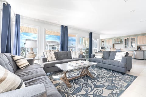 The serene and airy living area includes sofa/loveseat set, side seating, cable TV, and sliding glass door that opens to spacious ocean view deck