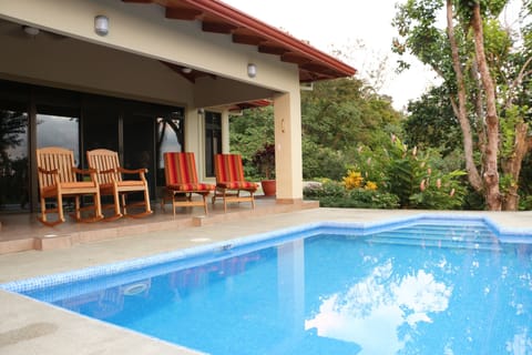 Pool with covered patio. Rocking chairs and chaise  lounges