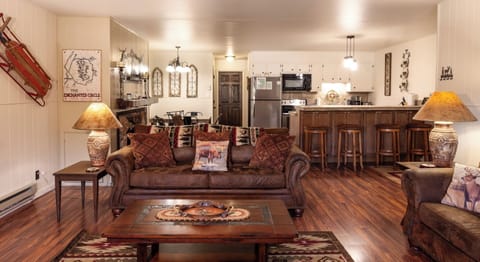 Step into your cozy retreat with rustic charm and modern comforts. The open living area invites you to unwind on plush leather sofas while warm lamps and unique decor create a welcoming atmosphere. Your fully-equipped kitchen awaits, perfect for preparing 