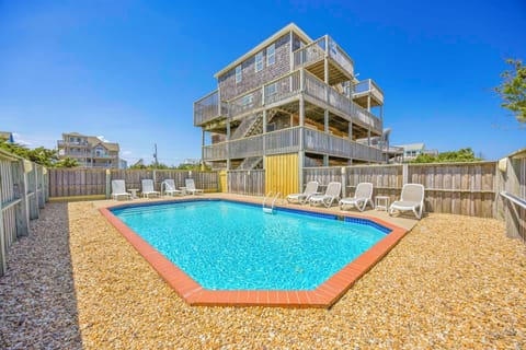 Modern beachside property with private swimming pool and sun loungers in fenced yard.