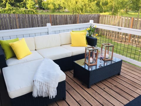 Comfortable outdoor couch's adjacent to table with 4 chairs and Weber BBQ