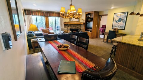 Living room with wood fireplace, dining table, and balcony w/ propane BBQ grill