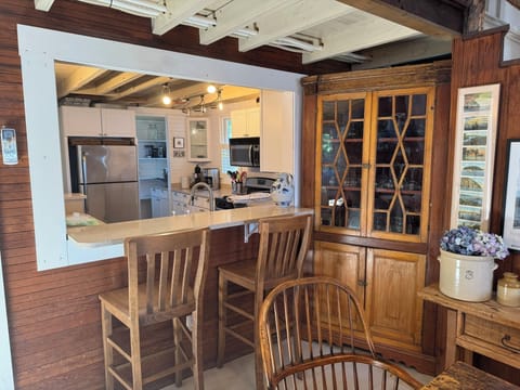 View to kitchen from dining; corner cupboard with glassware.
