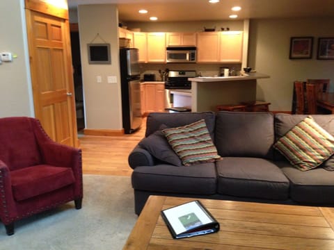 Pantry door at left, counter stools behind the couch, Welcome book on the table.