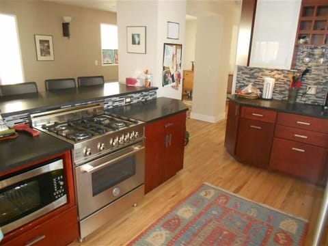 Gourmet kitchen with stainless appliances, glass backsplash, and cherry cabinets