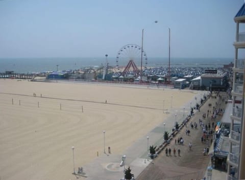 Balcony view of Ocean City boardwalk, beach, ocean, & amusement rides.