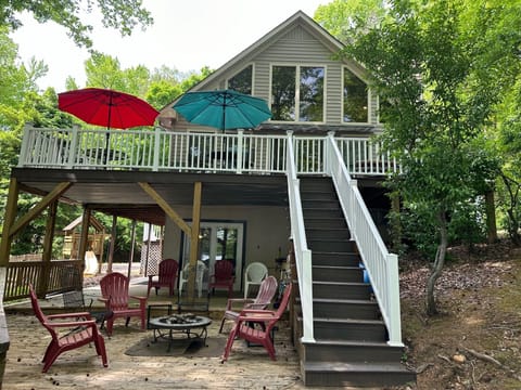 Two patio tables with chairs on main level deck with umbrellas and lakeview