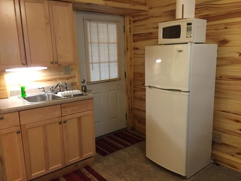 Kitchenette with refrigerator, microwave, dishes, and utensils. 