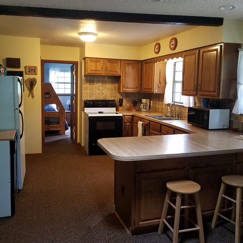 Kitchen with view of fridge, dishwasher, and 3 barstools, breakfast island