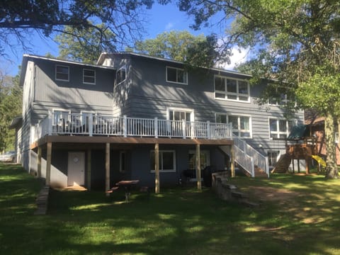 View of back of Lake Home with yard, large deck, and play set.  