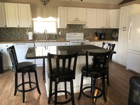 Eating area with 6 counter stools and large granite surface.