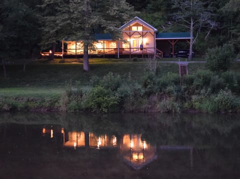 The cabin reflects in the New River as night settles in.