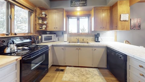 Full kitchen with cooking utensils, small appliances, pots/pans, & dishes.