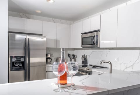 Contemporary kitchen has new quartz counters, backsplash and bar.