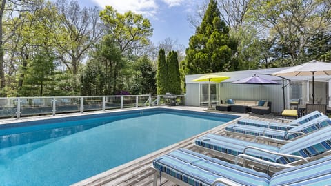huge swimming pool and deck surrounded by trees

