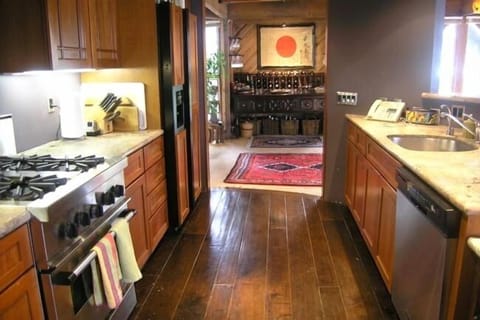 Professional kitchen with gas appliances, hardwood accents, looking toward bar