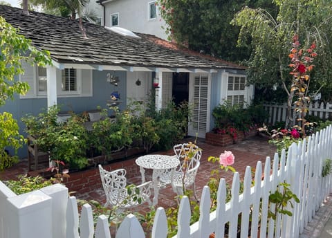 Front patio with teak table and bistro set surrounded by flowers