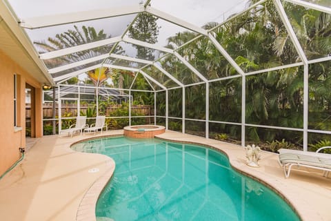 Free form swimming pool with spa and fully enclosed cage and lush landscaping