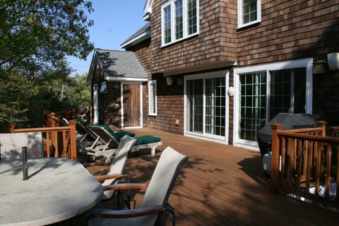 Back deck of house, with outdoor shower in background. Dining area on left