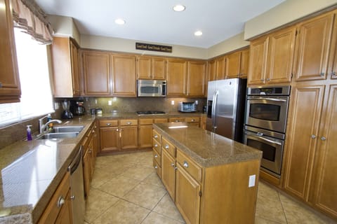 Large, fully stocked kitchen with island, stainless appliances, refrigerator