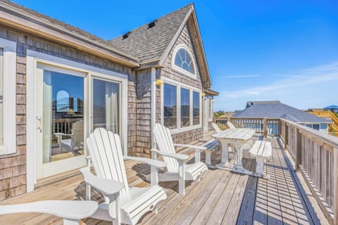 A spacious upper-level deck with white Adirondack chairs and coastal views, perfect for morning coffee or evening sunsets in this charming shingled beach cottage.
