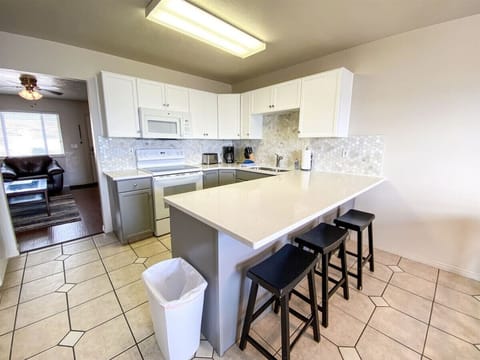 Bright and spacious kitchen with quartz countertops, modern appliances, and convenient breakfast bar seating.