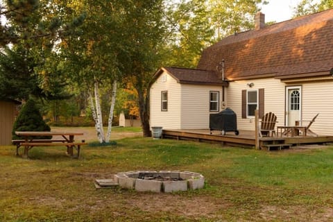 Outdoor space including deck with charcoal grill, outdoor seating and fire pit.