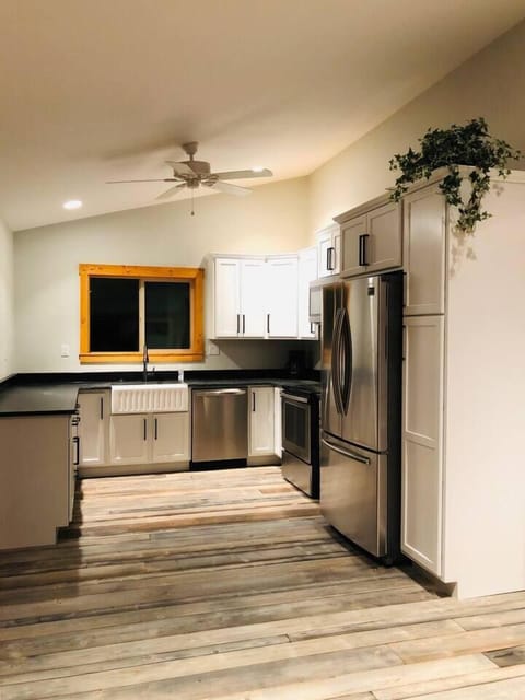 The charming kitchen features stainless steel appliances, plenty of counter space, natural lighting, and basic cookware and utensils.