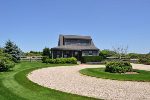 Front of home with circular stone drive and porch.