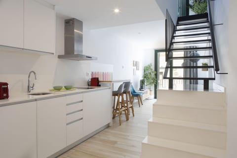 The Urban Suites Sitges holiday apartment has a kitchen equipped with a dishwasher, microwave, juicer, kettle, coffee maker and toaster. The kitchen is ceramic hob. In this photo you can see the stairs that go up to the bedroom.