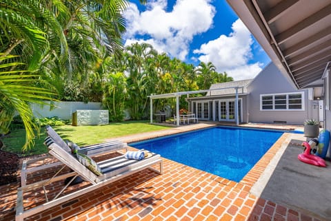 Step onto your private patio where a sparkling pool awaits, framed by lush palms and manicured lawn—your tropical retreat for sun-soaked relaxation.