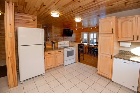 Kitchen opens to dining space has 75" 4K Smart TV, L-shape bar, custom tables. 