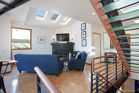 A fireplace and TV for the sofas. Glass stairs lead to the roof deck.