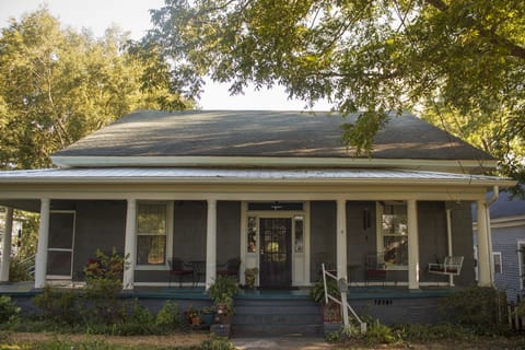 Front view of house. Stairwell to apartments on left side of front porch.