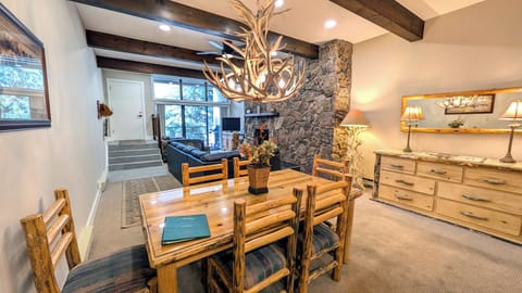 Living room w/ wood fireplace, dining table, and balcony with propane BBQ grill